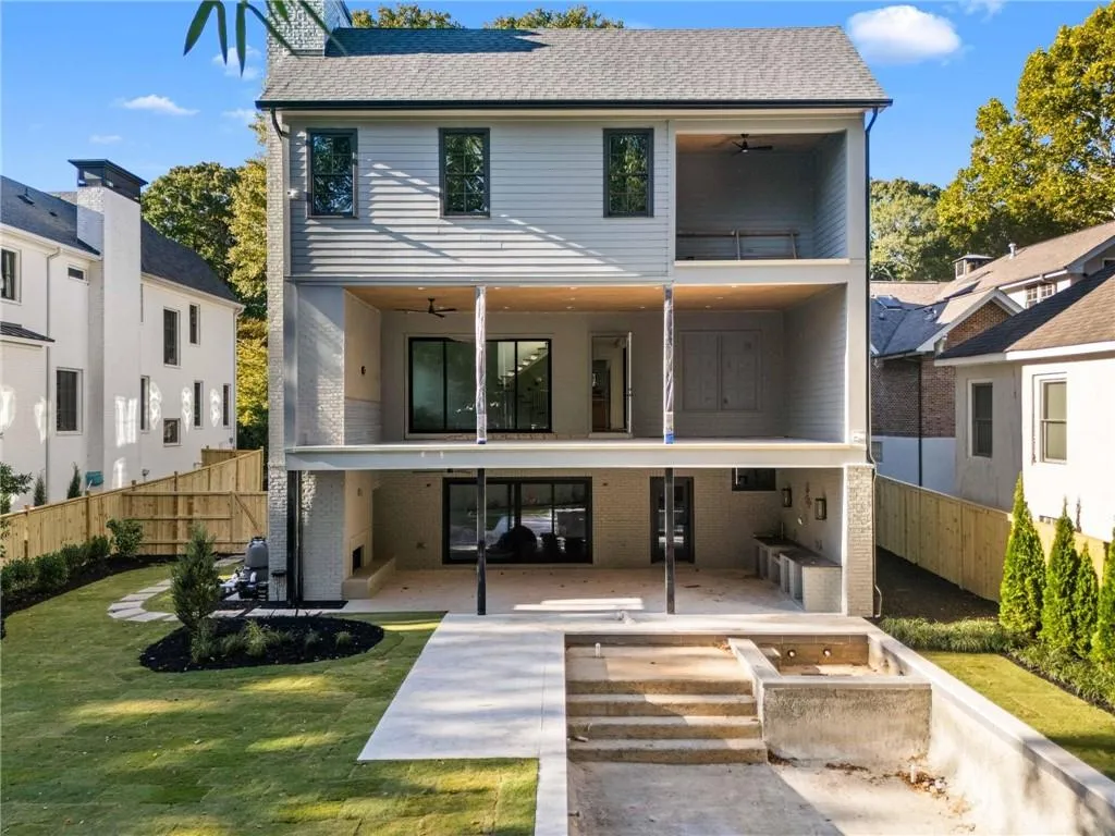 Back of house with a ceiling fan, a fenced backyard, a balcony, a patio, and roof with shingles