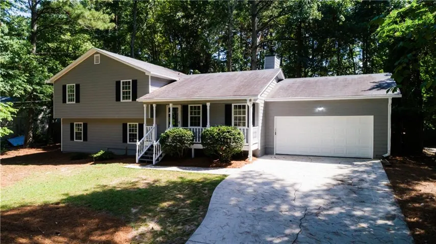 Siding exterior with a covered porch, white railings, and an attached garage