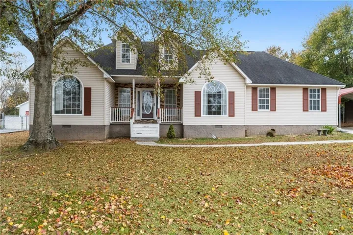 Traditional-style home featuring a covered front porch, dormer windows, arched window, and a carport