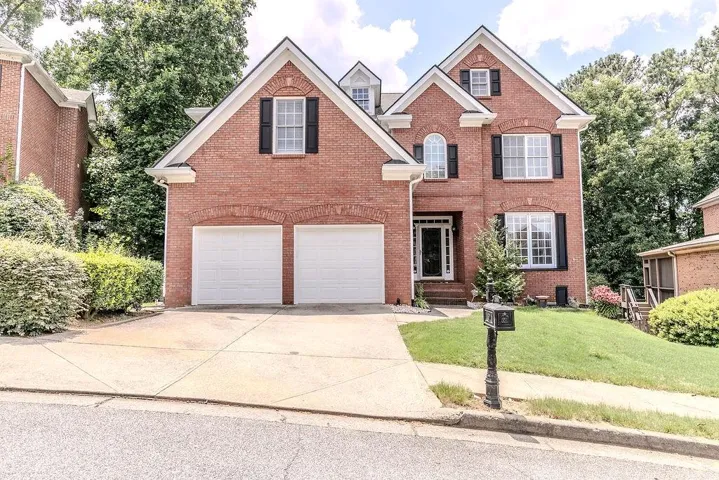 Two-story brick facade residence featuring a two-car garage, arched window accents, and multiple dormer windows