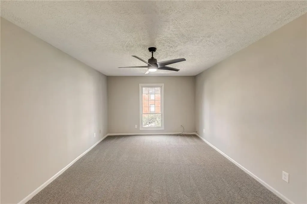Unfurnished room featuring light colored carpet, ceiling fan, and a textured ceiling