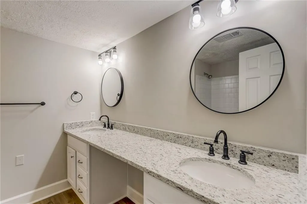 Bathroom featuring a textured ceiling, hardwood / wood-style flooring, and dual vanity