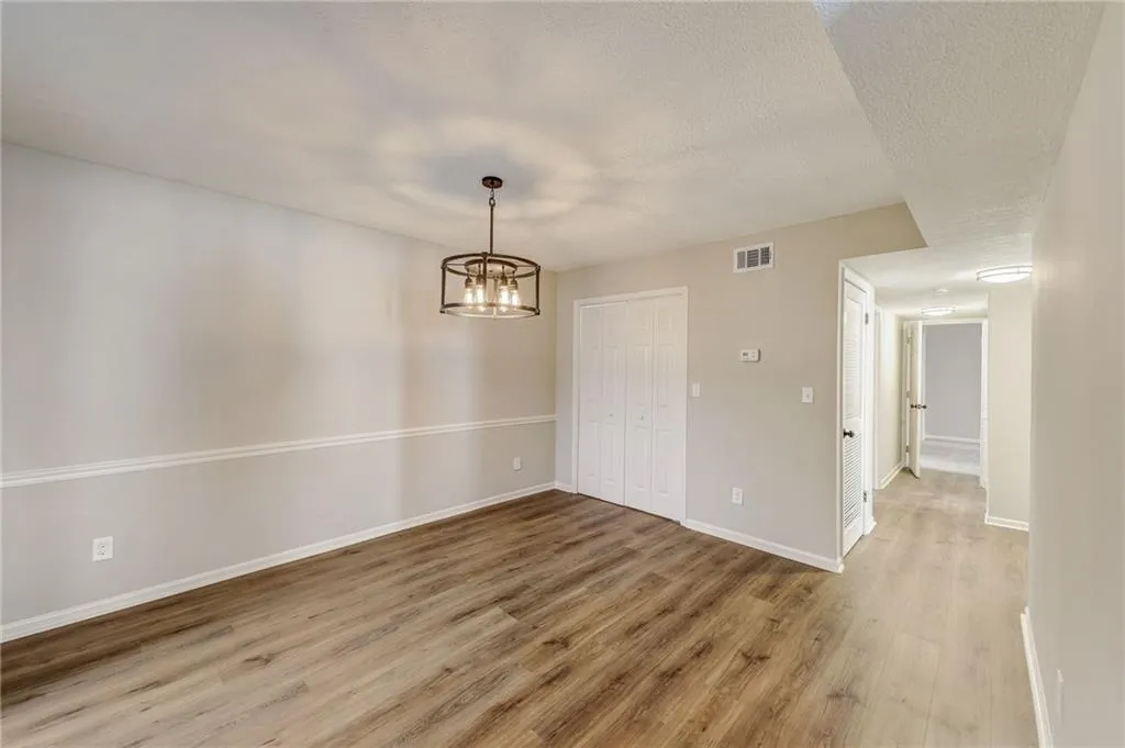Unfurnished room with hardwood / wood-style flooring, an inviting chandelier, and a textured ceiling