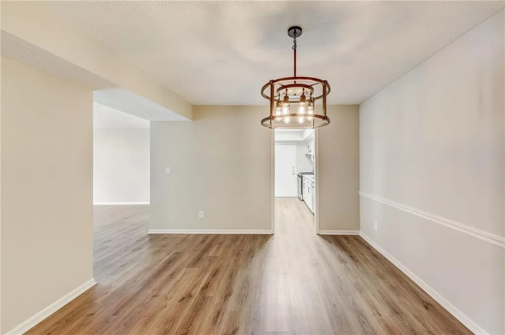Empty room featuring light wood-type flooring and a chandelier