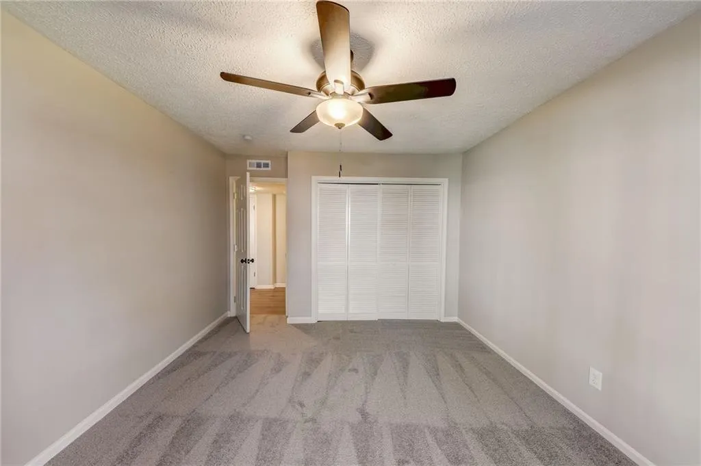 Unfurnished bedroom featuring a textured ceiling, carpet floors, and ceiling fan