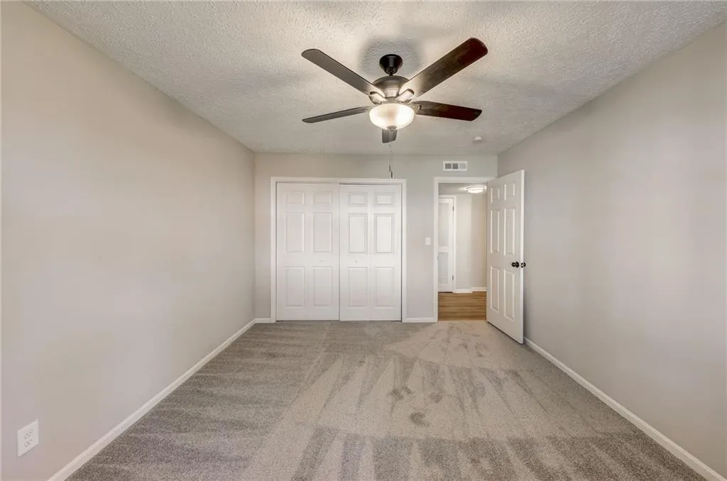 Unfurnished bedroom with a closet, a textured ceiling, ceiling fan, and light carpet
