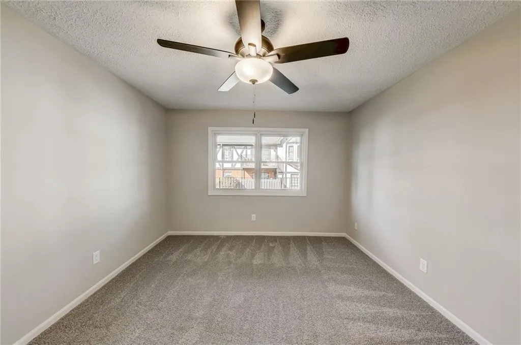 Unfurnished room with a textured ceiling, ceiling fan, and carpet flooring