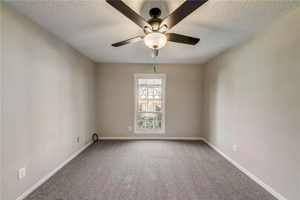 Carpeted spare room featuring ceiling fan and a textured ceiling