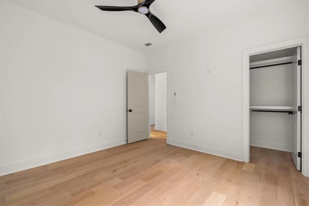 Unfurnished bedroom with light wood-style floors, ceiling fan, and a spacious closet