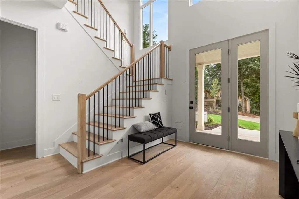 Doorway with wood finished floors, a high ceiling, and stairway