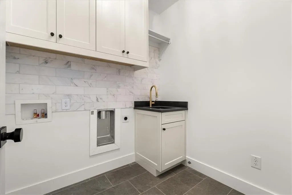 Laundry area featuring cabinet space, dark tile patterned flooring, hookup for a washing machine, and electric dryer hookup