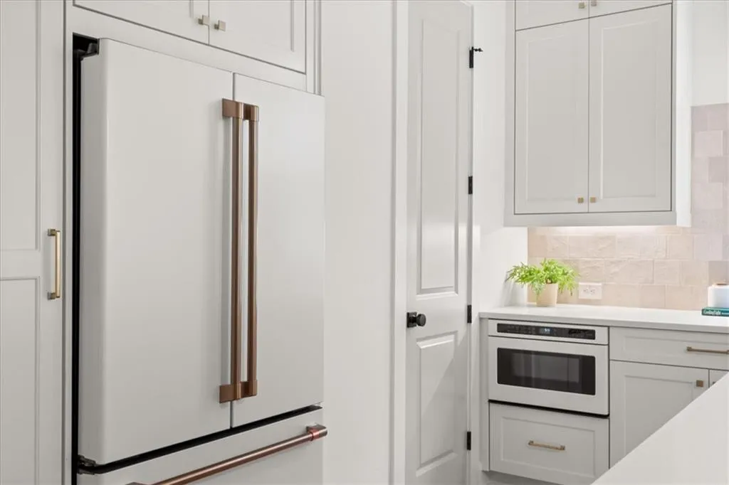 Kitchen with white cabinetry, white appliances, backsplash, and light stone counters