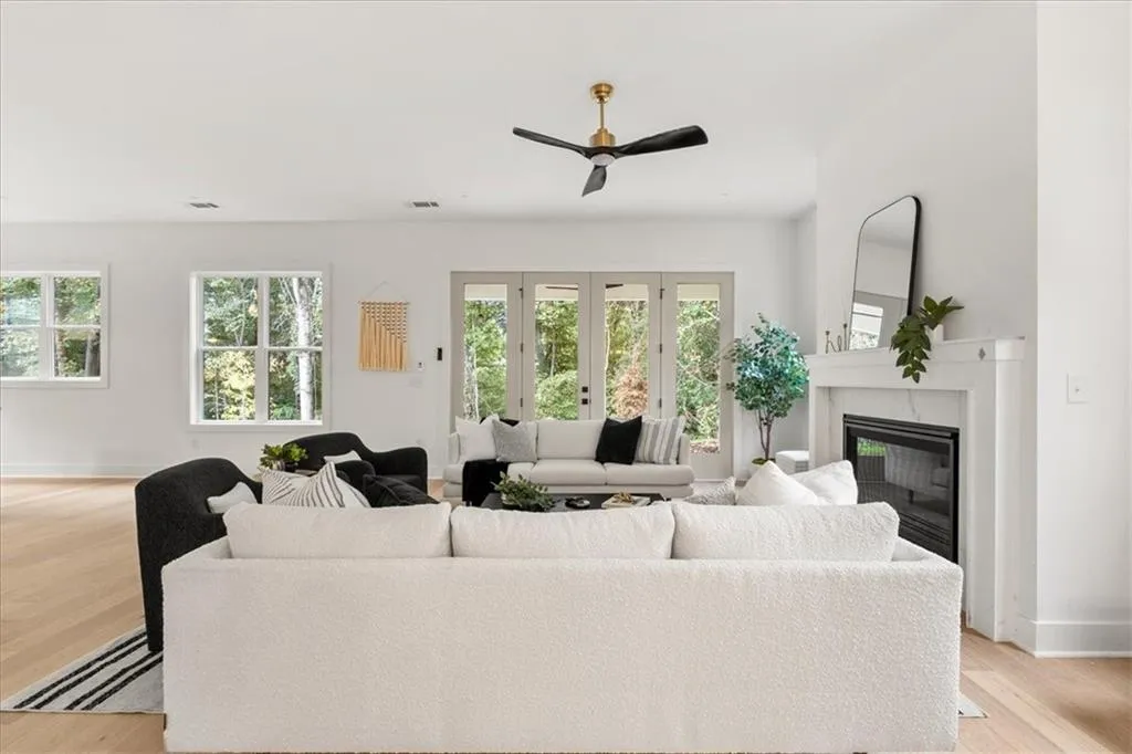 Living area featuring light wood-style flooring, a high end fireplace, and ceiling fan
