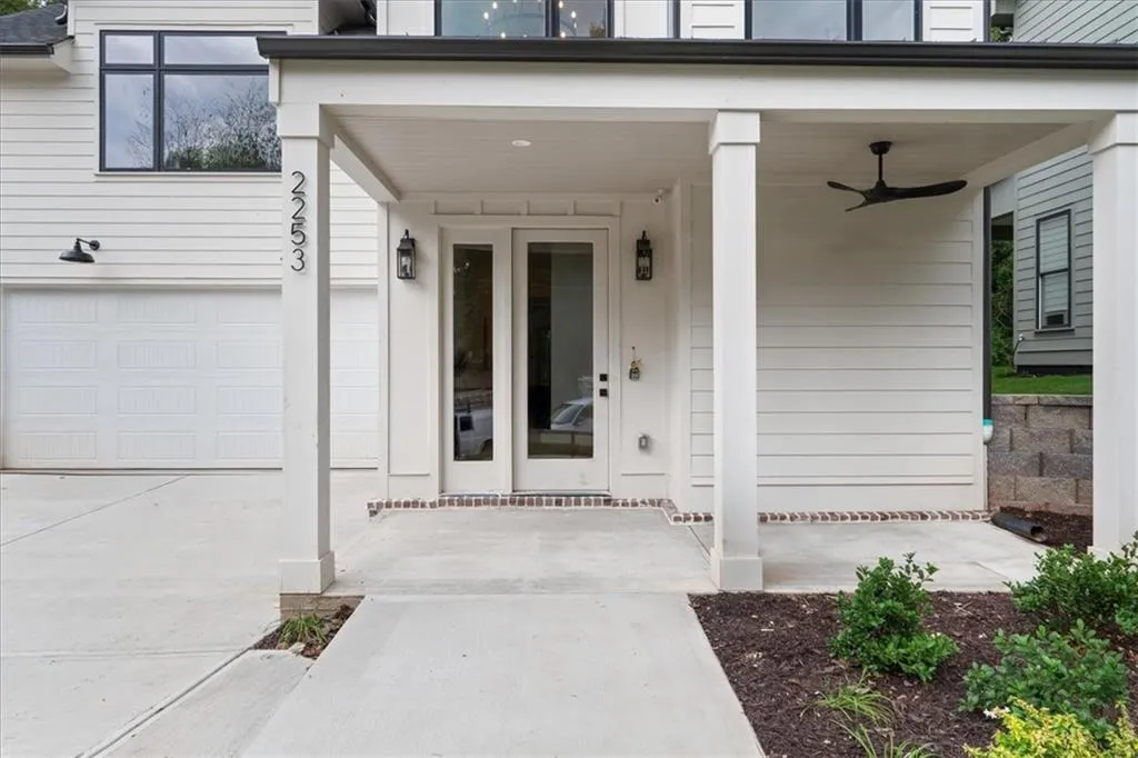 Entrance to property with covered porch, a garage, concrete driveway, and a ceiling fan