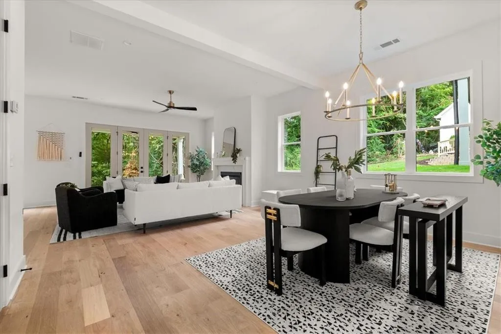 Dining area featuring light wood-style flooring, a fireplace, beam ceiling, a ceiling fan, and a chandelier