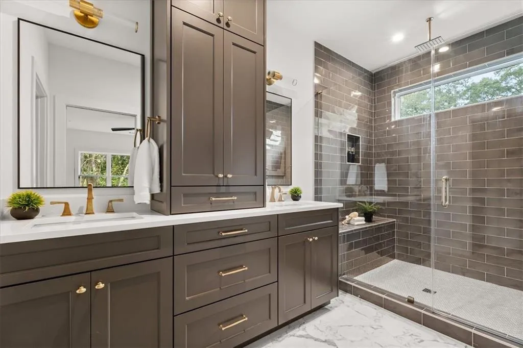 Full bathroom featuring a shower stall, double vanity, light marble finish floors, and recessed lighting