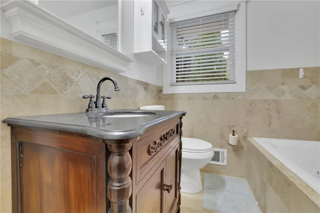 Bathroom featuring toilet and tile walls