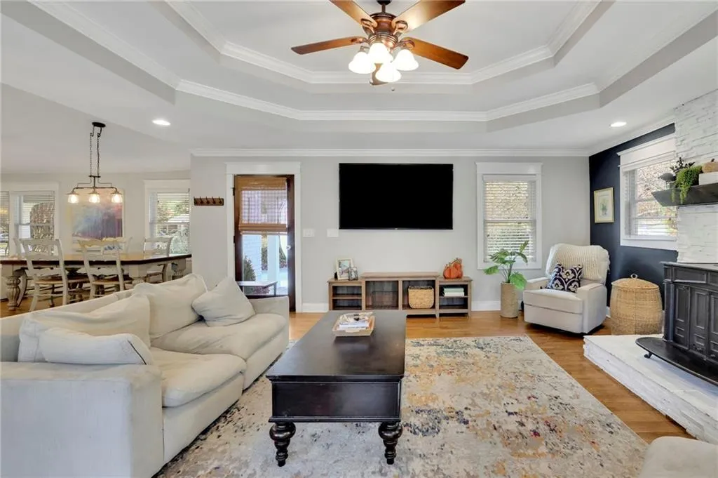 Living room featuring a tray ceiling, light hardwood / wood-style flooring, ceiling fan, and crown molding