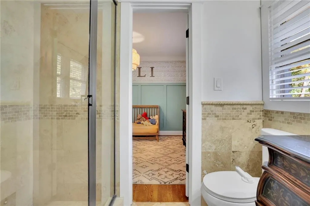 Bathroom with hardwood / wood-style floors, toilet, walk in shower, and tile walls