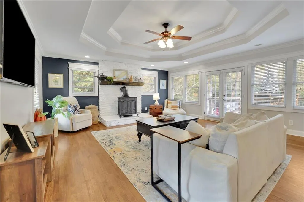 Living room with a raised ceiling, crown molding, plenty of natural light, and light wood-type flooring