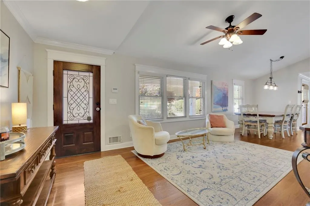 Foyer entrance with ceiling fan with notable chandelier, wood-type flooring, ornamental molding, and vaulted ceiling
