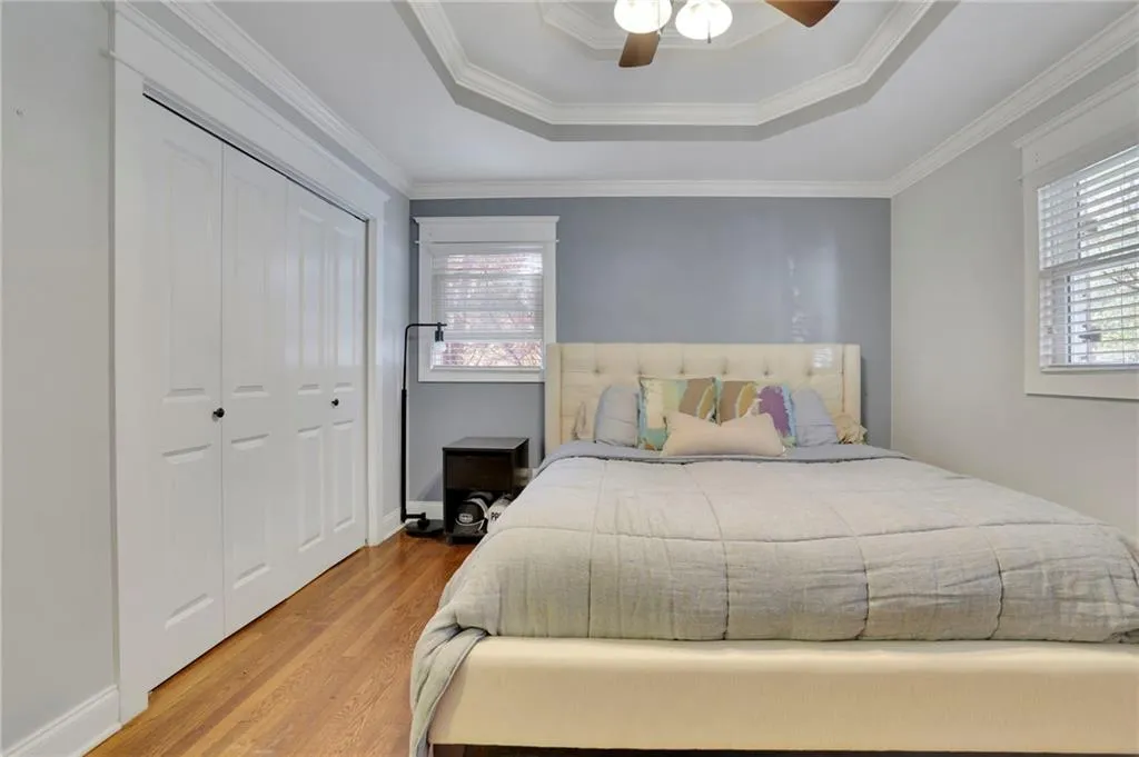 Bedroom with ceiling fan, wood-type flooring, ornamental molding, and a closet