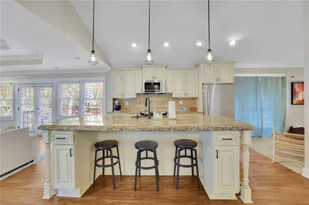 Kitchen with pendant lighting, light stone countertops, stainless steel appliances, and cream cabinets