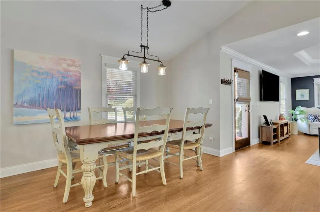 Dining space with vaulted ceiling, light hardwood / wood-style flooring, and ornamental molding