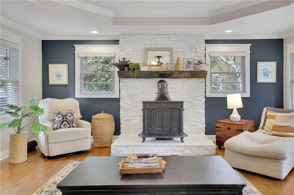 Living room featuring a raised ceiling, crown molding, light hardwood / wood-style flooring, and a healthy amount of sunlight