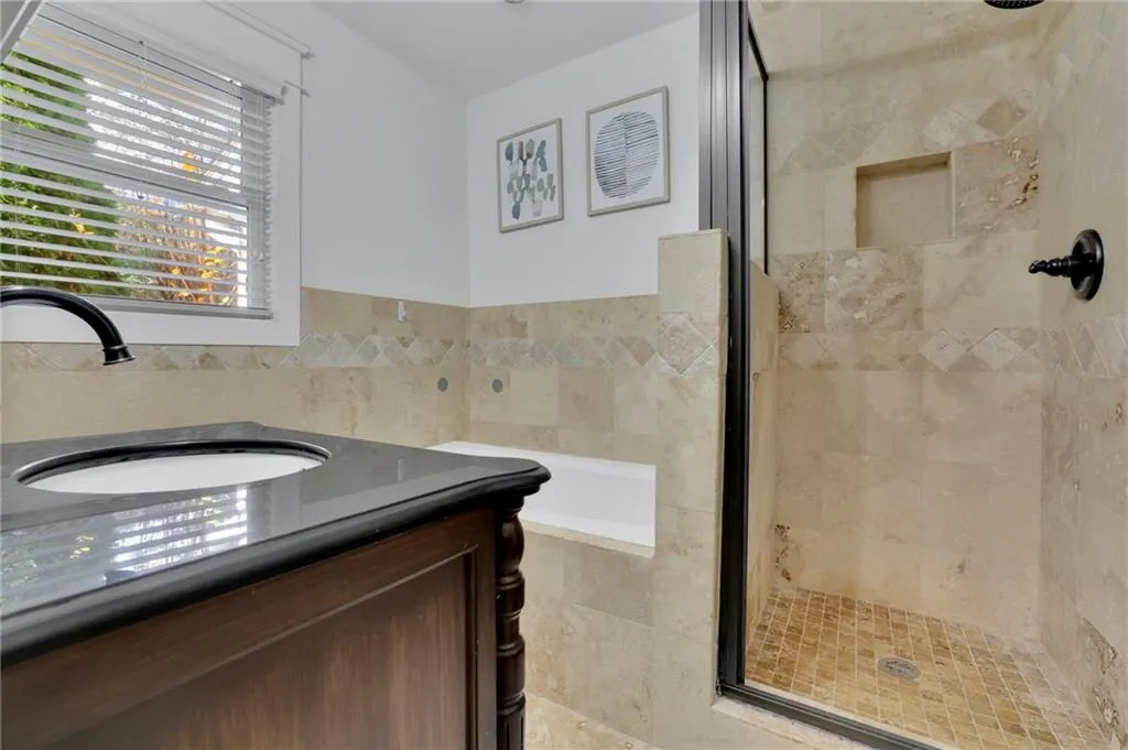 Bathroom featuring vanity, independent shower and bath, and tile walls