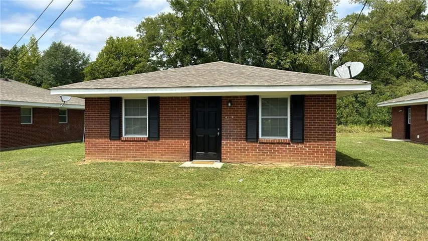 Ranch-style home featuring a front yard, brick siding, and roof with shingles