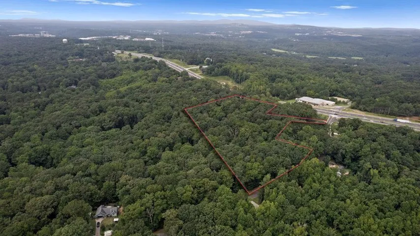 Expansive wooded parcel outlined in red, featuring direct highway frontage and dense tree coverage