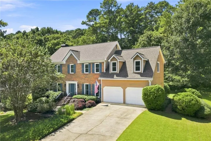 Brick and siding exterior with a gabled roofline, dormer windows, and a two-car garage