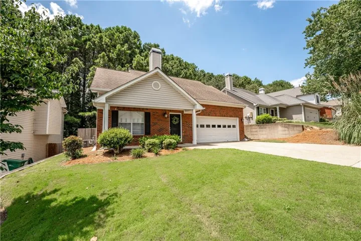 Brick exterior with siding accents, attached garage, concrete driveway, and established front landscaping