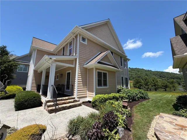Two-story residence featuring light beige siding, white trim, and a covered porch with white columns