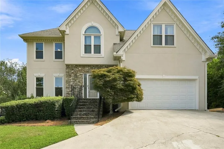 Stucco exterior with stone accents, a prominent arched window, and an attached two-car garage