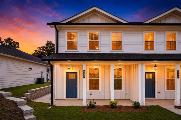Modern townhouse exterior featuring white siding, a dark roof, and blue entry doors