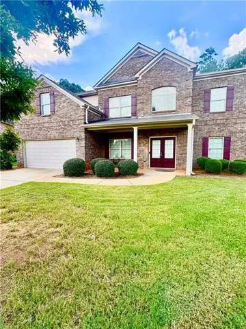 Two-story brick exterior with gabled roofline, two-car garage, and covered front entry