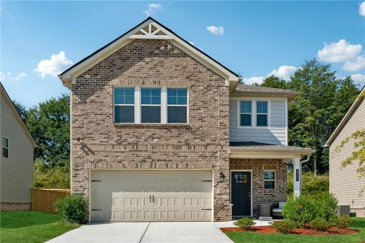 View of front facade featuring covered porch, concrete driveway, an attached garage, and brick siding