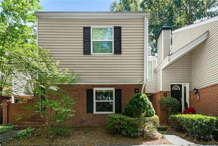 Brick and siding exterior with black shutters and mature landscaping