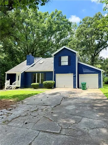 Two-story residence featuring a blue siding exterior, a front porch with white railings, a multi-car driveway, and two garage doors