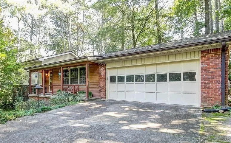 Front exterior featuring a covered porch with wooden pillars, horizontal wood-panel siding, and brick accents