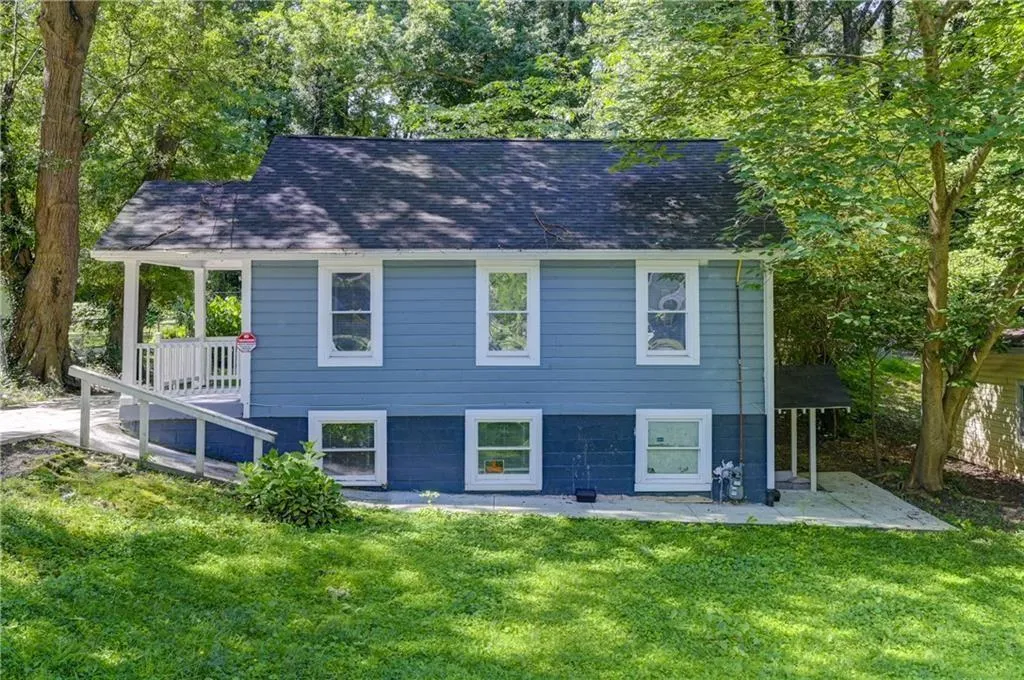 View of front of house featuring a front yard, a shingled roof, and a patio area