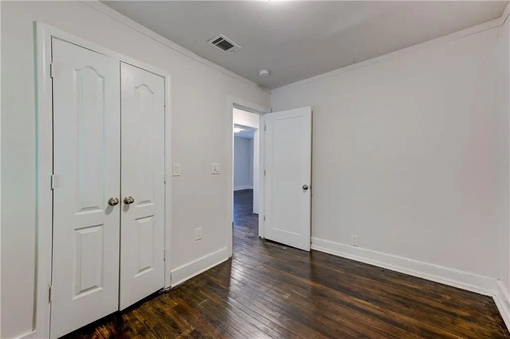 Unfurnished bedroom featuring crown molding, dark wood-type flooring, and a closet
