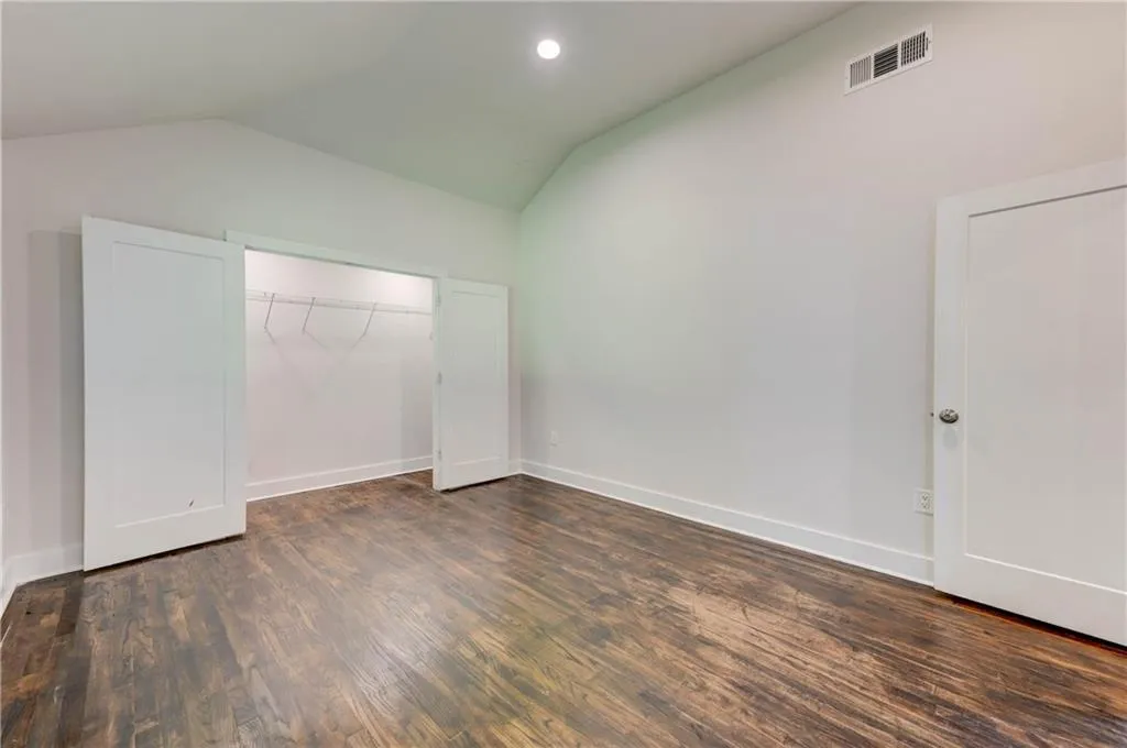 Unfurnished bedroom with lofted ceiling, dark wood finished floors, a closet, and recessed lighting