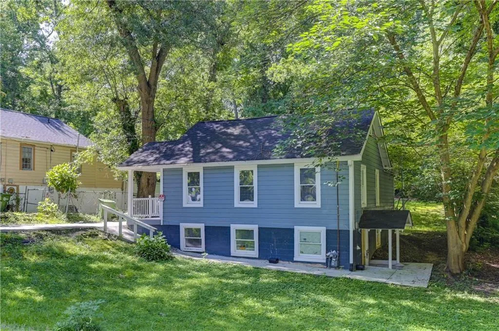 View of front facade featuring a front yard, roof with shingles, and a patio