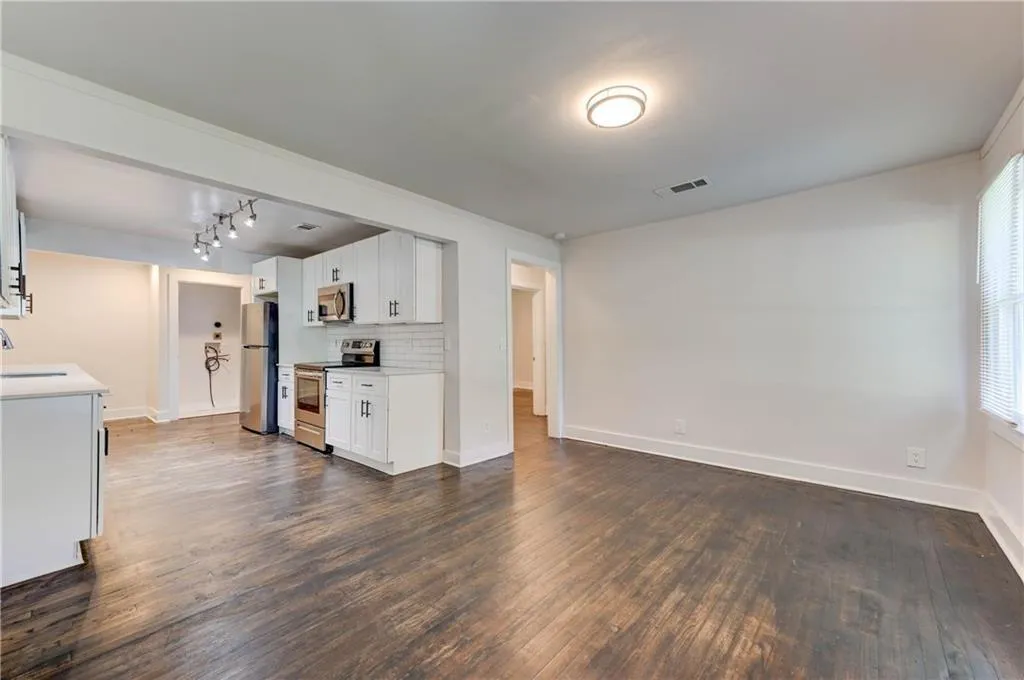 Unfurnished living room featuring dark wood-type flooring and rail lighting