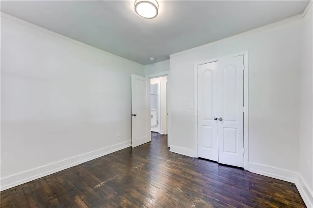 Unfurnished bedroom with ornamental molding, a closet, and dark wood finished floors