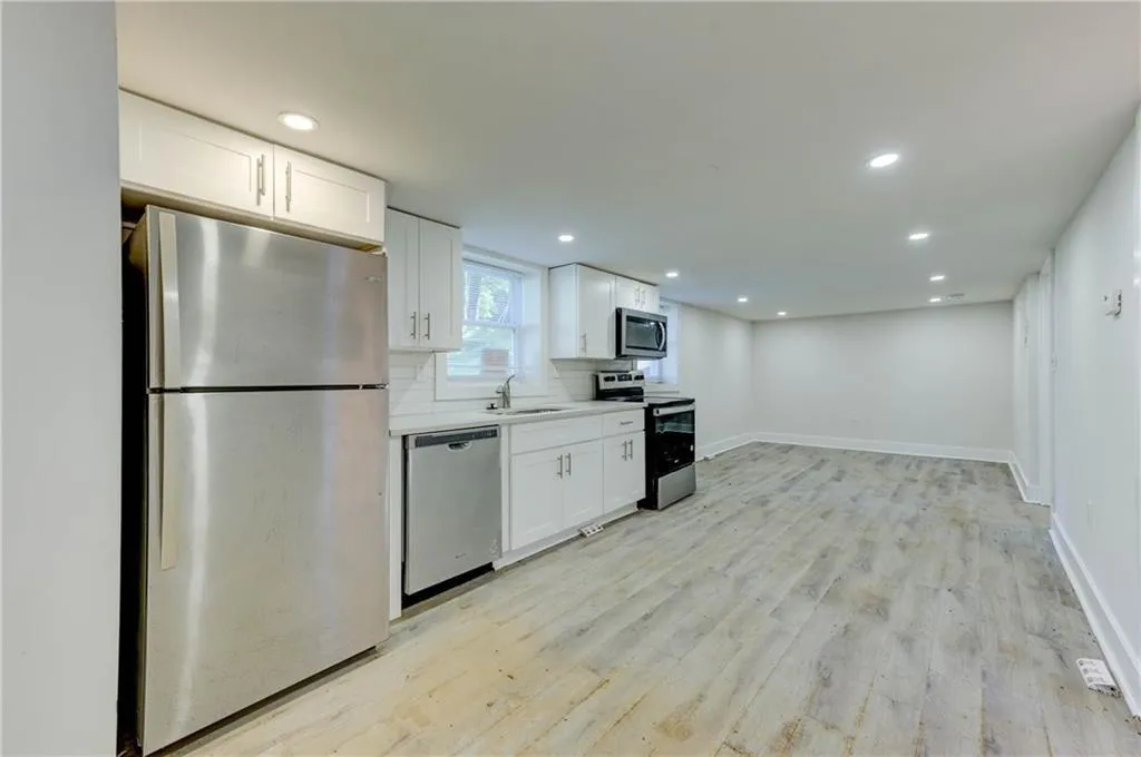 Kitchen with appliances with stainless steel finishes, light countertops, white cabinets, light wood-type flooring, and recessed lighting