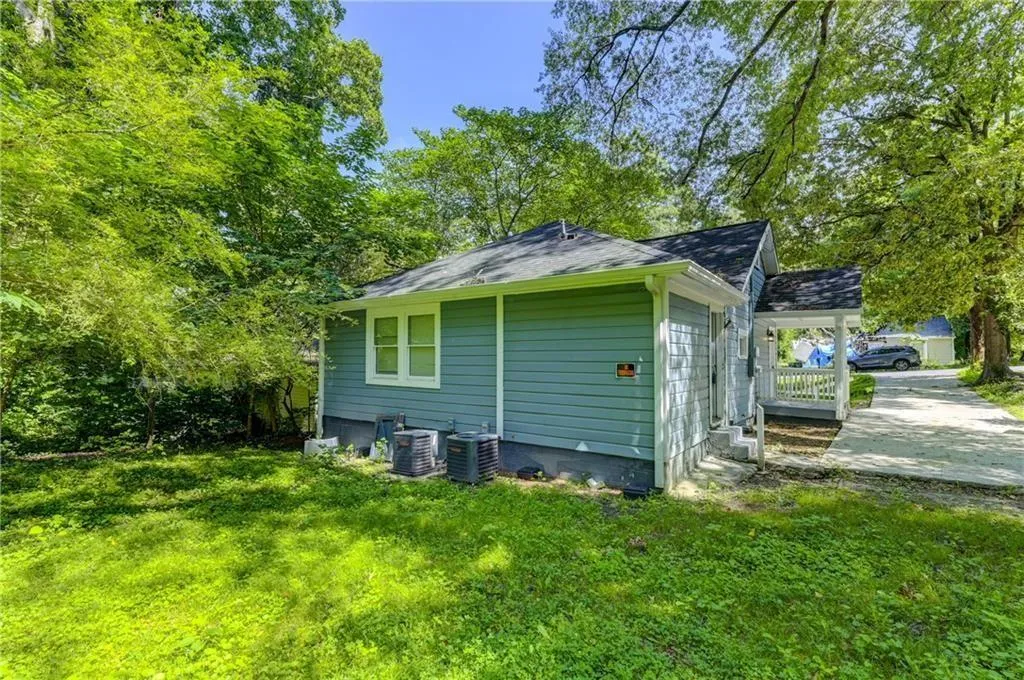 View of property exterior with a yard, a porch, and a shingled roof